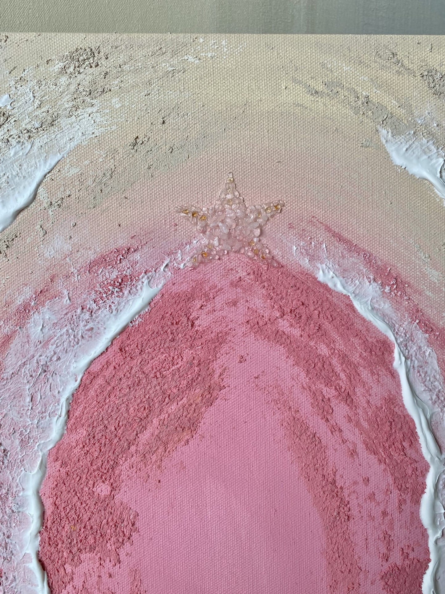Detailed view of starfish made with rose quartz and citrine crystals on pink sand-textured abstract painting.