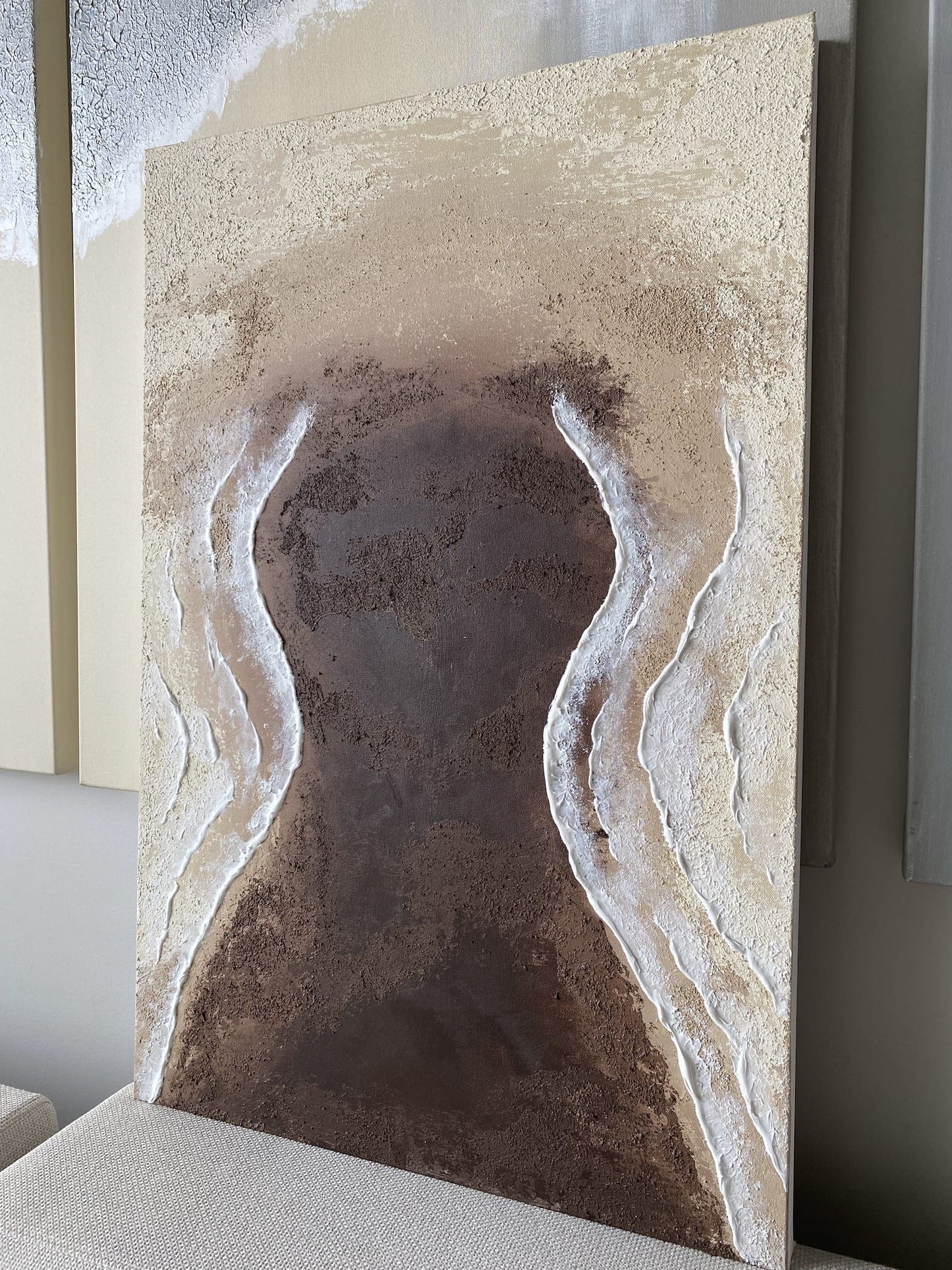 Full view of "Body of Water No. 1" – abstract shoreline-inspired painting photographed in natural light, showing textured surface and organic earth tones.